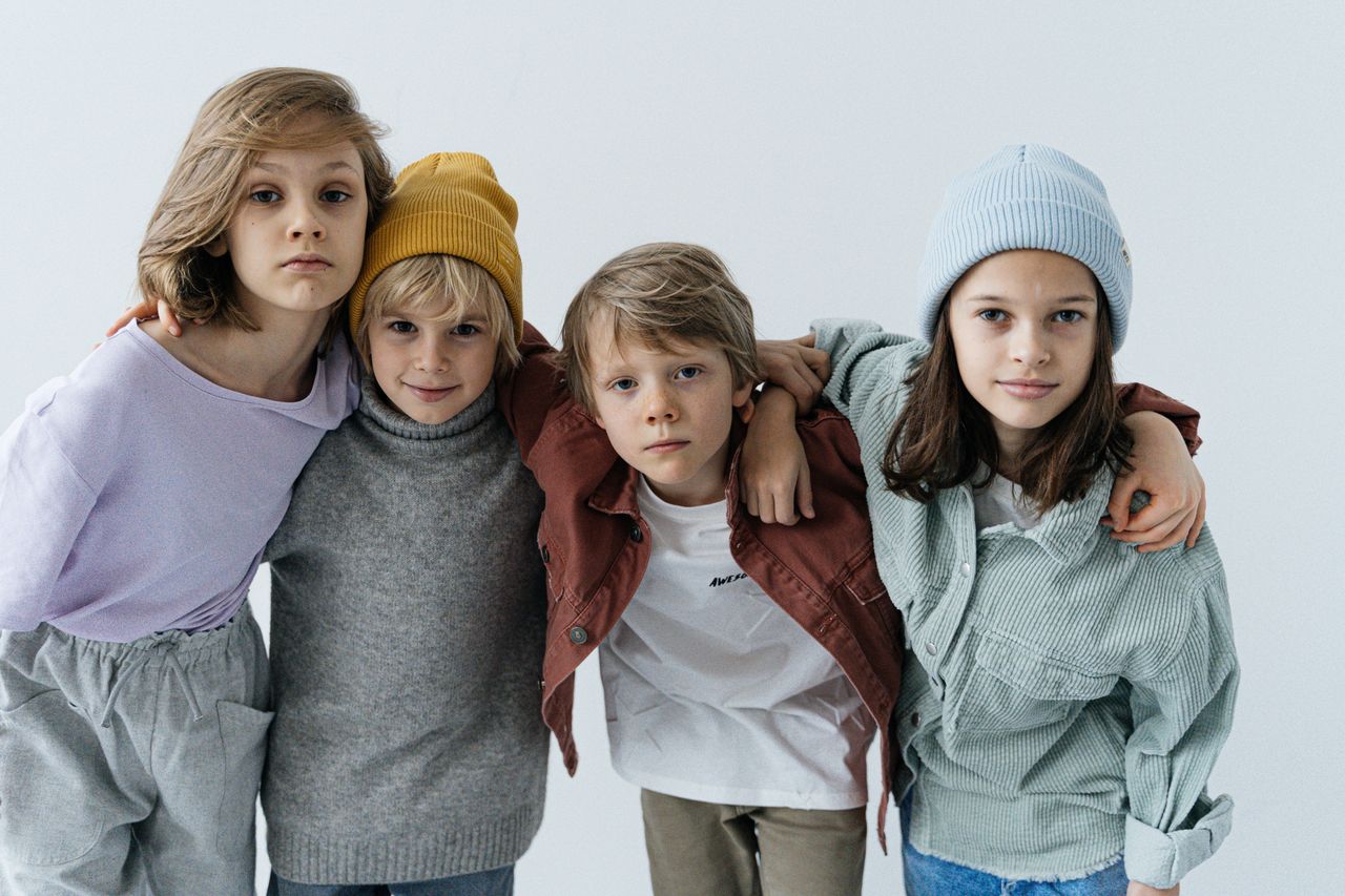 quality-assurance-02 Children posing together in trendy casual outfits with hats indoors.